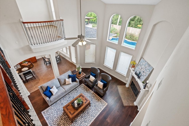 living room featuring a fireplace, a high ceiling, dark hardwood / wood-style flooring, and ceiling fan