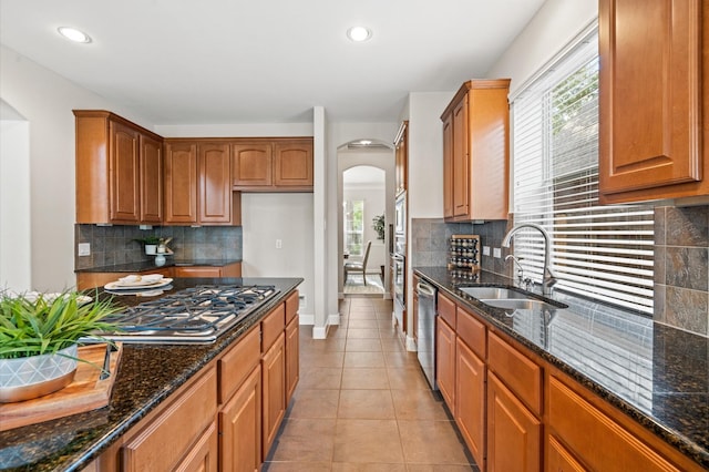 kitchen with tasteful backsplash, sink, dark stone counters, and appliances with stainless steel finishes