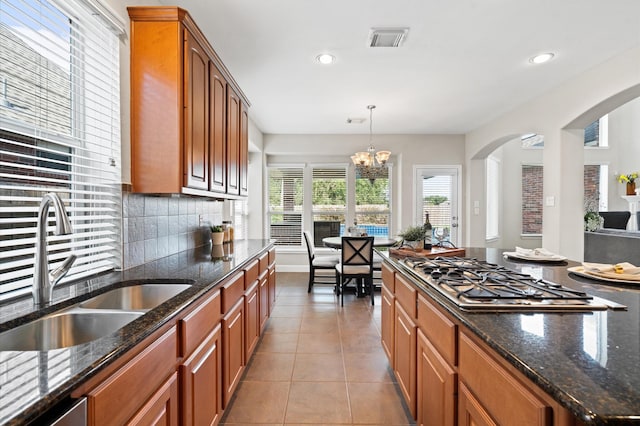 kitchen with backsplash, an inviting chandelier, sink, decorative light fixtures, and stainless steel gas cooktop