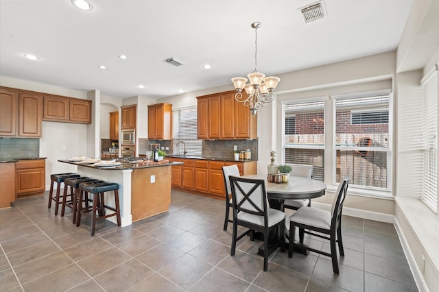 kitchen with a center island, hanging light fixtures, a chandelier, decorative backsplash, and appliances with stainless steel finishes