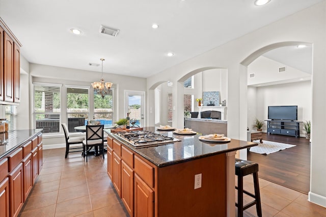 kitchen with light hardwood / wood-style flooring, dark stone countertops, a chandelier, pendant lighting, and a kitchen island