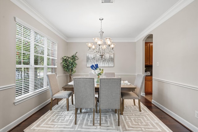 dining space featuring wood-type flooring, ornamental molding, and an inviting chandelier