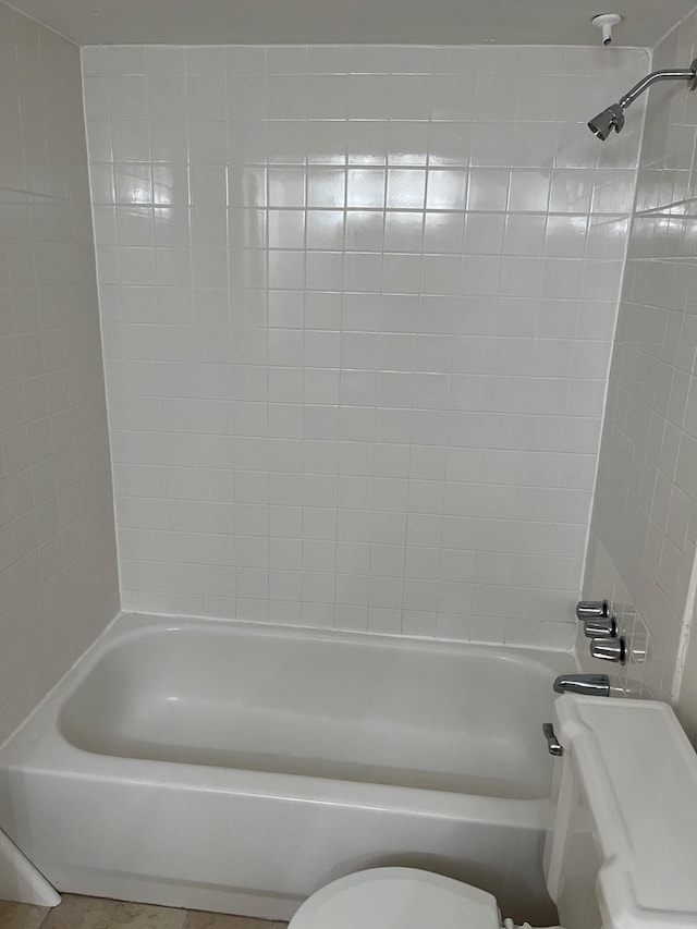 bathroom with tiled shower / bath combo and toilet