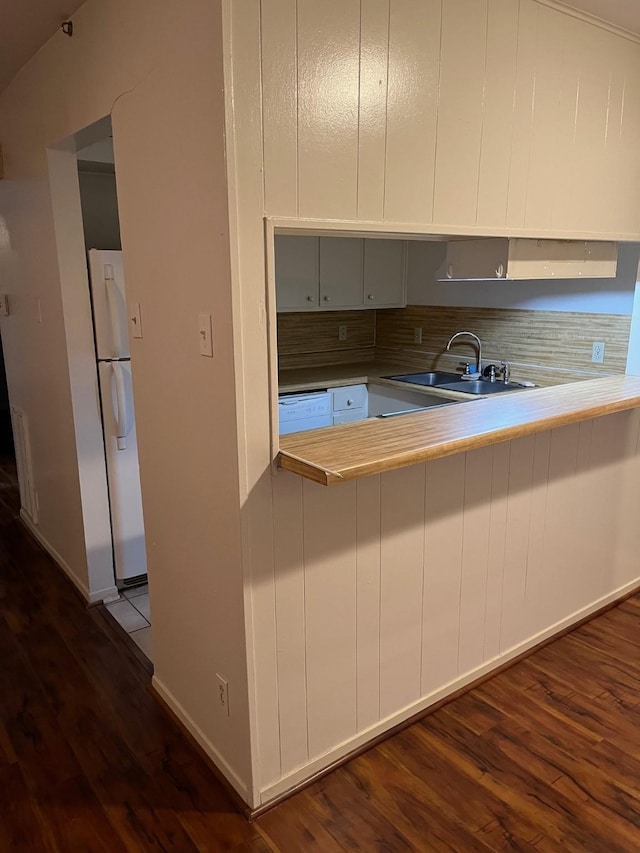 kitchen featuring hardwood / wood-style flooring, kitchen peninsula, white appliances, and sink