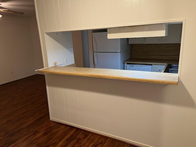 kitchen featuring ceiling fan, sink, dark wood-type flooring, kitchen peninsula, and white appliances