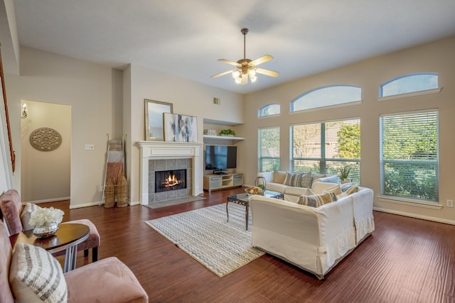 living room featuring ceiling fan, dark hardwood / wood-style flooring, and a tiled fireplace