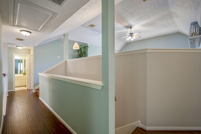 hallway featuring wood-type flooring, a textured ceiling, and lofted ceiling