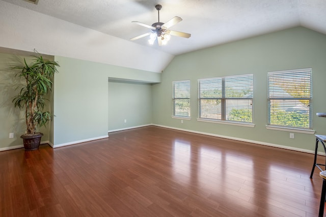 empty room featuring dark hardwood / wood-style floors, vaulted ceiling, and ceiling fan