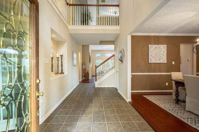 foyer entrance featuring ornamental molding, dark wood-type flooring, and a towering ceiling