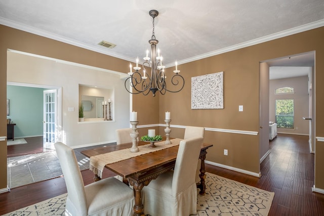 dining area featuring dark hardwood / wood-style flooring, crown molding, and an inviting chandelier