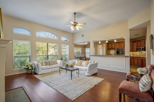 living room featuring ceiling fan, dark hardwood / wood-style flooring, and a high ceiling