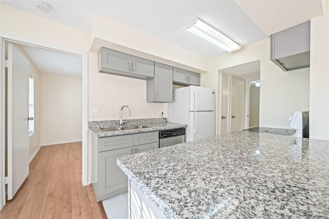 kitchen with light hardwood / wood-style floors, light stone counters, white appliances, and sink