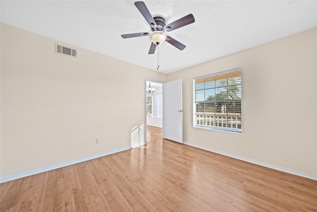 spare room featuring ceiling fan with notable chandelier, a textured ceiling, and light hardwood / wood-style flooring