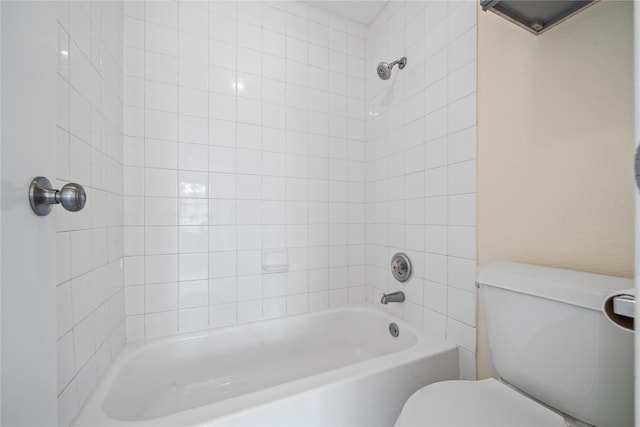 bathroom with tiled shower / bath combo and toilet