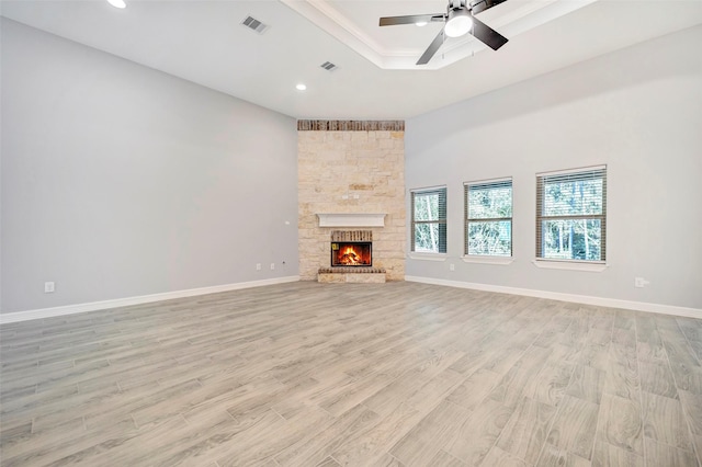 unfurnished living room with ceiling fan, a fireplace, and light wood-type flooring