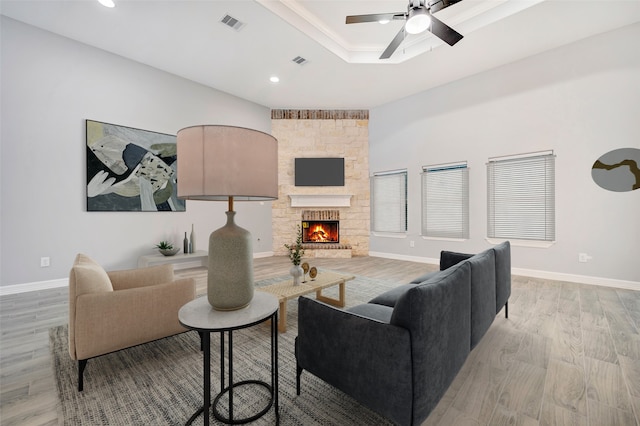 living room featuring a fireplace, light wood-type flooring, and ceiling fan