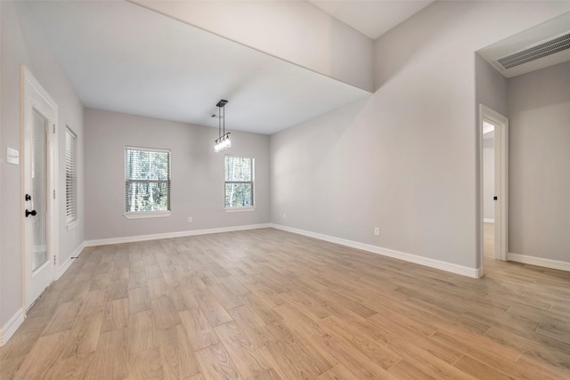 spare room featuring an inviting chandelier and light wood-type flooring