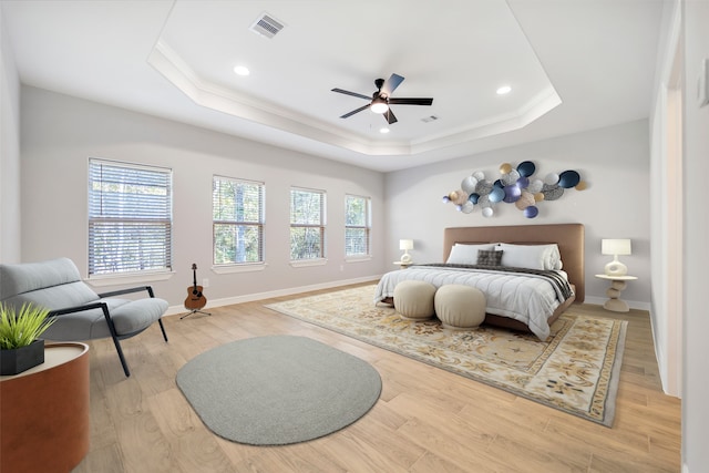 bedroom with ceiling fan, light wood-type flooring, crown molding, and a tray ceiling