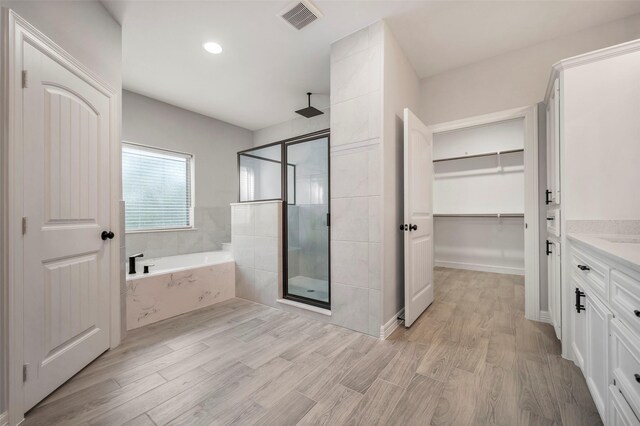 250 Broadmoor Dr, Huntsville, TX 77340 - full bathroom featuring visible vents, wood finished floors, a shower stall, vanity, and a walk in closet