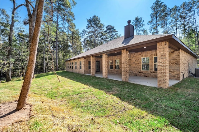 rear view of house featuring central air condition unit, a patio area, and a yard