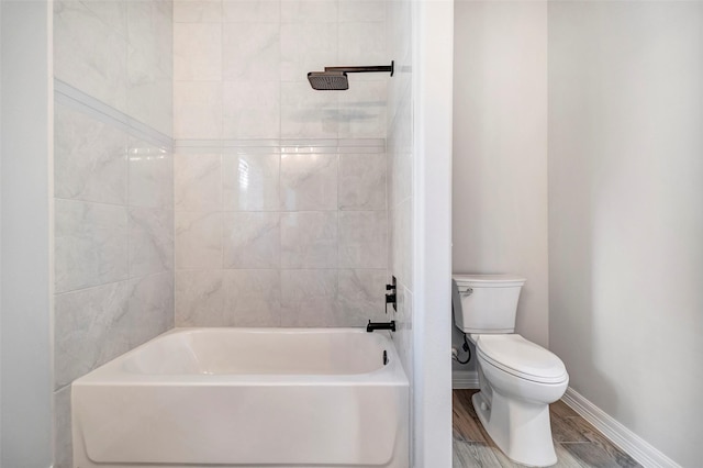 bathroom with hardwood / wood-style floors, tiled shower / bath combo, and toilet