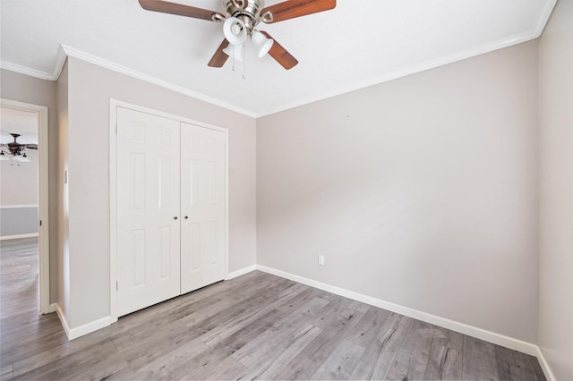 unfurnished bedroom with a closet, light hardwood / wood-style floors, ceiling fan, and crown molding