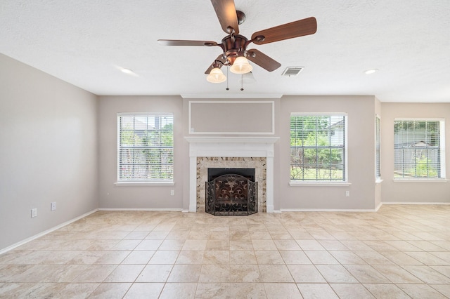 unfurnished living room with a fireplace, light tile patterned flooring, plenty of natural light, and ceiling fan