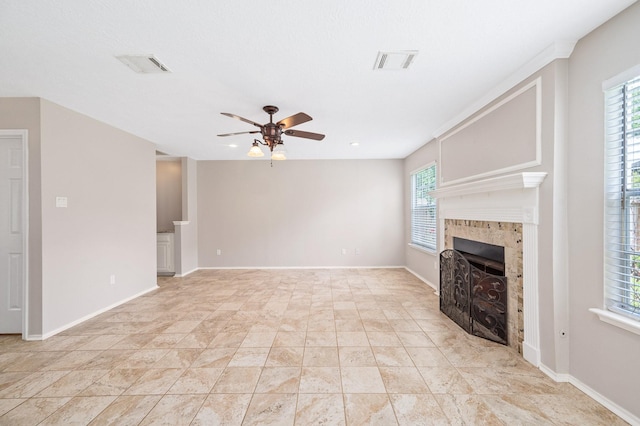 unfurnished living room featuring a tile fireplace, a wealth of natural light, and ceiling fan