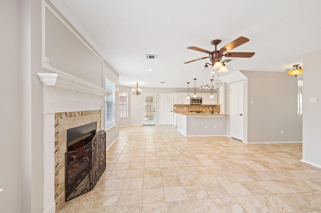 unfurnished living room with ceiling fan with notable chandelier, sink, and a fireplace