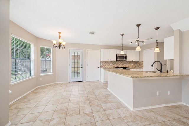 kitchen featuring sink, tasteful backsplash, kitchen peninsula, white cabinets, and appliances with stainless steel finishes