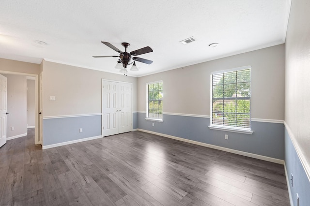 unfurnished room with a textured ceiling, dark hardwood / wood-style floors, ceiling fan, and ornamental molding