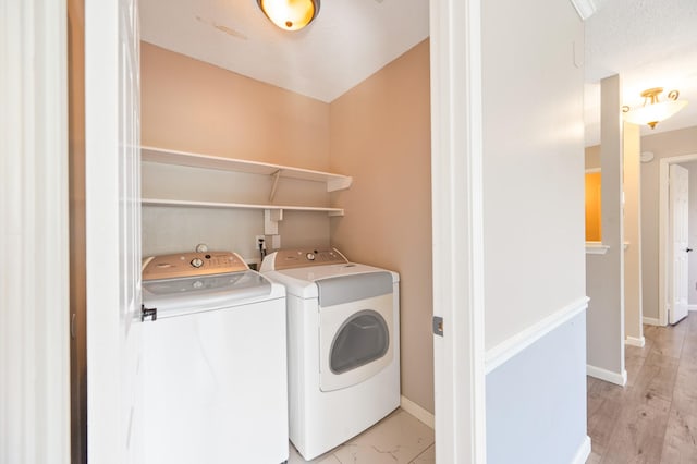 washroom with washing machine and dryer and light hardwood / wood-style flooring