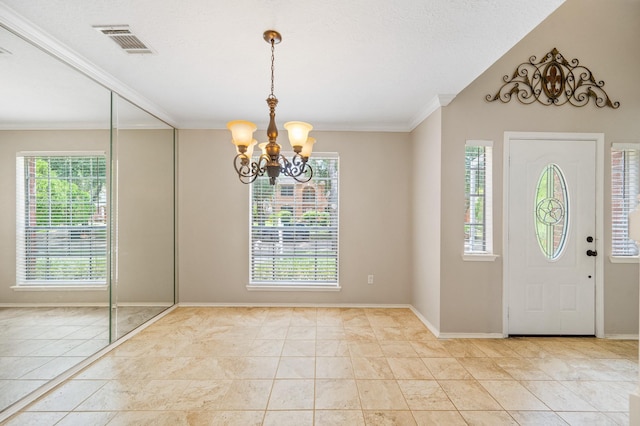 foyer with a healthy amount of sunlight, ornamental molding, light tile patterned floors, and a chandelier