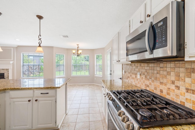 kitchen featuring a notable chandelier, pendant lighting, decorative backsplash, white cabinets, and appliances with stainless steel finishes