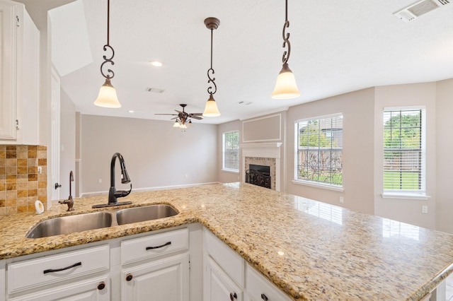 kitchen featuring pendant lighting, white cabinets, sink, ceiling fan, and tasteful backsplash