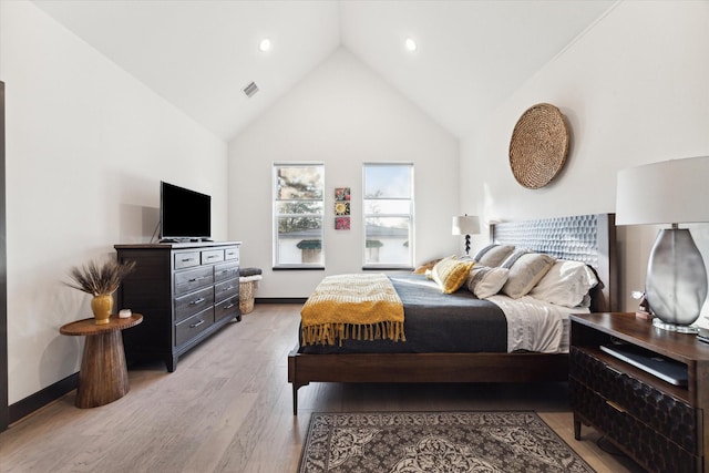 bedroom with high vaulted ceiling and light wood-type flooring