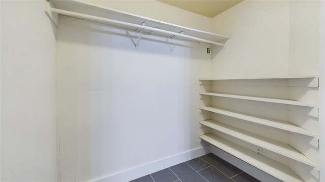 walk in closet with dark tile patterned flooring