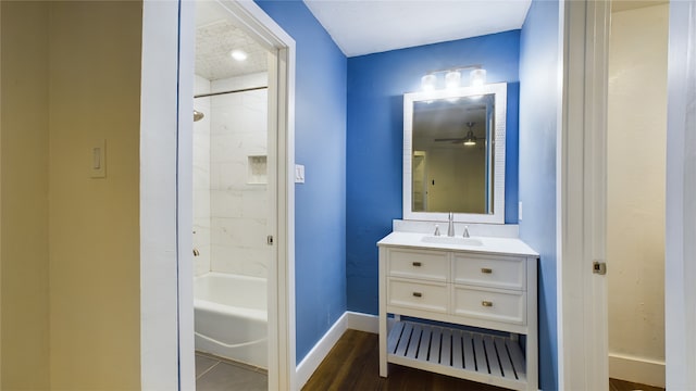 bathroom featuring vanity, baseboards, a ceiling fan, tub / shower combination, and wood finished floors