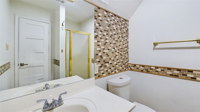 bathroom featuring sink, a shower with door, tile walls, and toilet