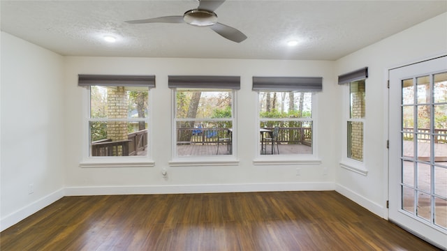 spare room featuring baseboards, ceiling fan, a wealth of natural light, dark wood finished floors, and a textured ceiling