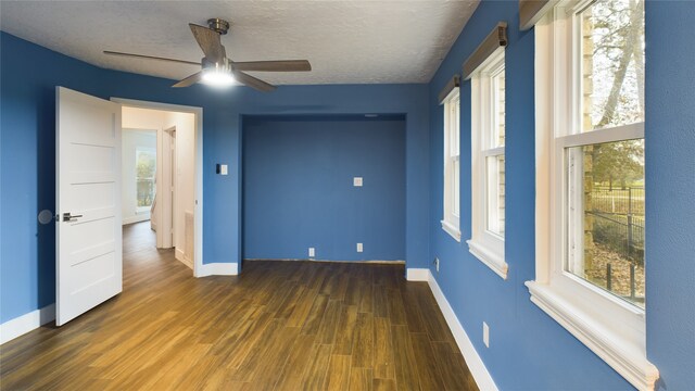 spare room featuring ceiling fan, plenty of natural light, dark wood-type flooring, and a textured ceiling