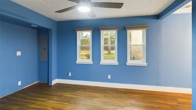 empty room featuring electric panel, ceiling fan, dark hardwood / wood-style floors, and a textured ceiling