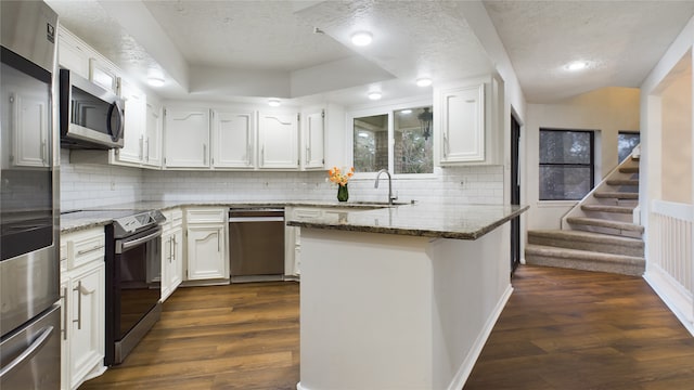 kitchen with a textured ceiling, appliances with stainless steel finishes, a sink, and white cabinetry