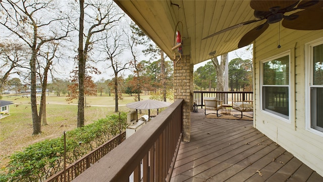 wooden terrace with a lawn and ceiling fan