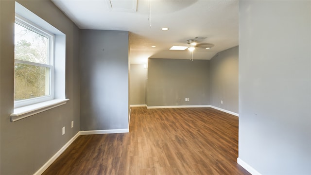unfurnished room featuring baseboards, attic access, and wood finished floors