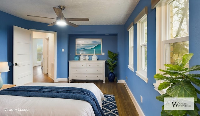 bedroom with baseboards, multiple windows, and wood finished floors