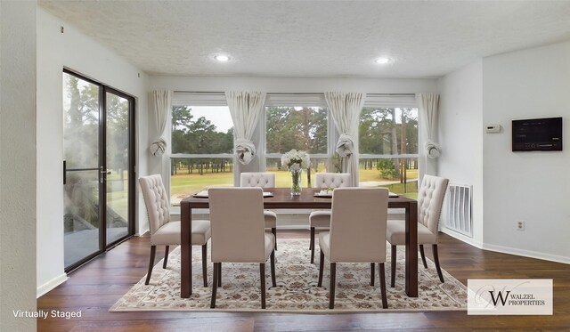 dining space with a textured ceiling, wood finished floors, baseboards, and visible vents