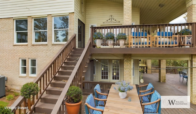back of house featuring brick siding, outdoor dining space, stairway, and a patio
