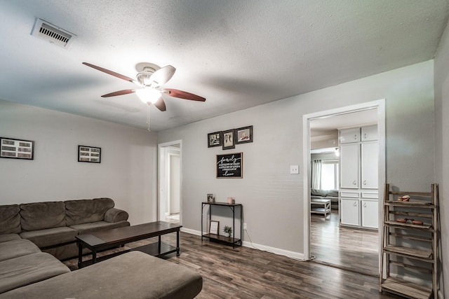 living room with ceiling fan, dark hardwood / wood-style flooring, and a textured ceiling