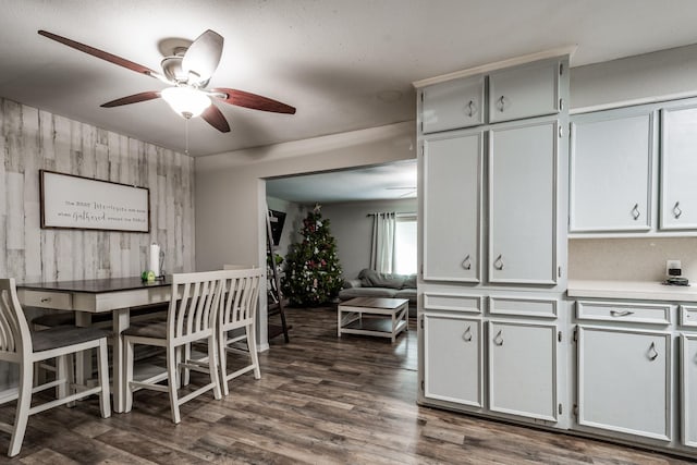 dining room featuring wood walls, dark hardwood / wood-style flooring, ceiling fan, and a textured ceiling